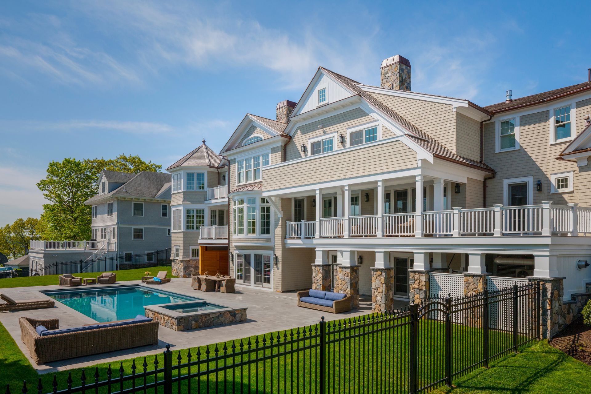 Backyard view of a shingle-style home with large pool, patio, and outdoor lounge space in Hingham, Massachusetts